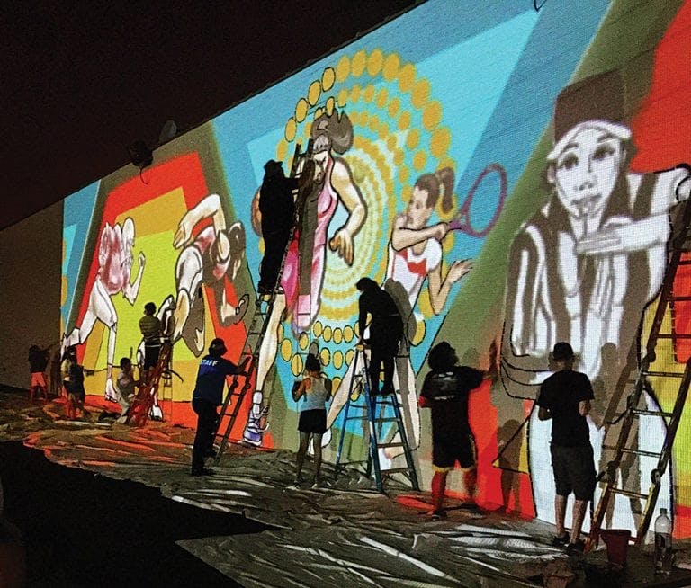 people painting a mural at night